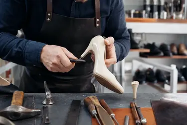 Profissional realizando troca de salto de sapato com ferramentas especializadas.